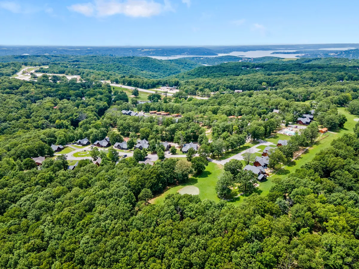 A sweeping view of rolling hills covered in lush greenery, with a sparkling lake visible in the background and a winding neighborhood road. The scene is peaceful and picturesque, ideal for sunset strolls and scenic drives described in the section.