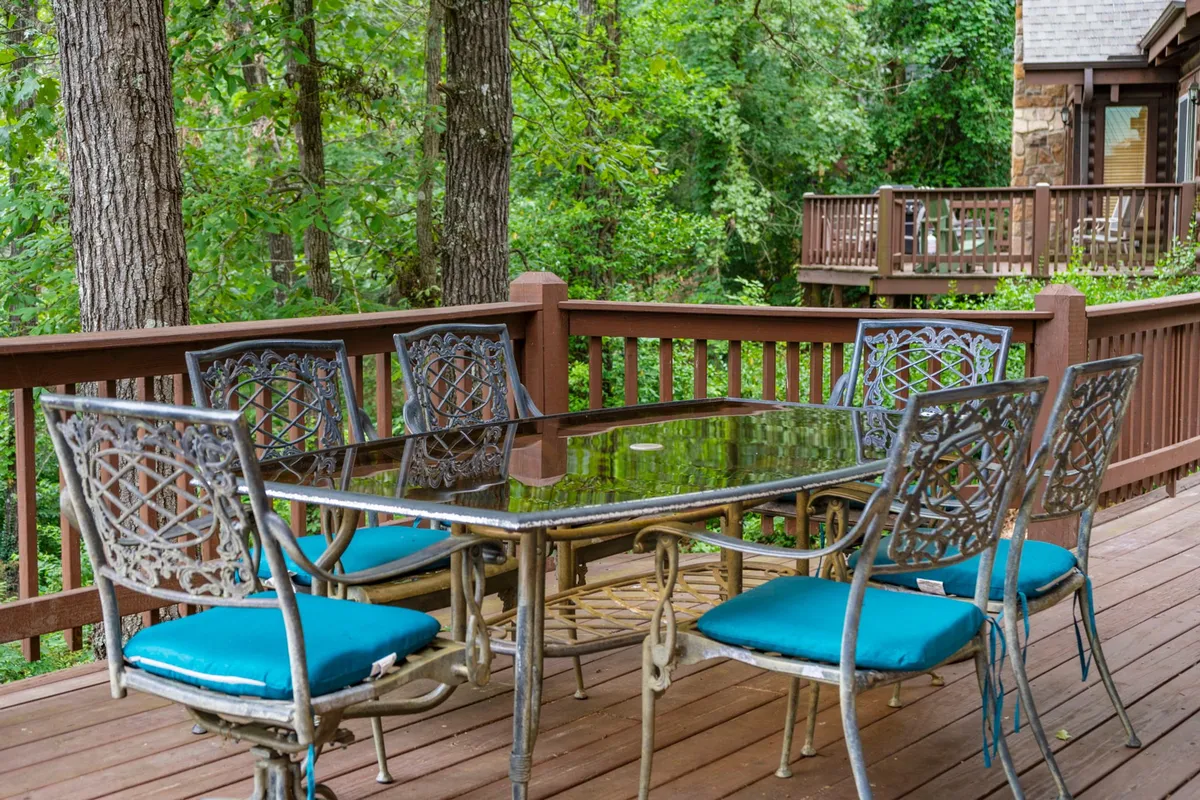 An elegantly set outdoor dining table and ornate chairs sit amidst lush greenery, inviting couples to enjoy a tranquil meal surrounded by nature. The soft evening light evokes the mood of a sunset dinner, echoing the idea of a romantic, candlelit meal near Big Cedar Lodge.